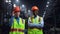 Multiethnic engineers smiling camera wearing safety uniform at huge factory.