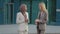 Multiethnic female colleagues discussing report outside. Happy businesswomen in office suits and hijab standing outdoors