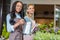 Multiethnic florists in aprons watering plants and smiling at camera