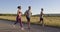 Multiethnic group of athletes running together on a panoramic countryside road. Diverse Team of joggers on morning