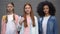 Multiethnic group of female students looking camera grey background, education