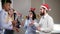 Multiethnic group of happy office workers holding Bengal lights and dancing wearing christmas hats and deer headband and