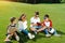 Multiethnic kids in sunglasses reading books on green meadow in park