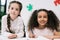 Multiethnic schoolgirls smiling at camera while studying together in classroom