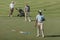 Multiethnic sportsmen standing with golf clubs on green pitch