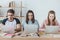 multiethnic students using laptops while sitting at table