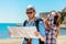 Multiethnic traveler couple using generic local map together on sunny day.