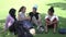 Multiethnic university female students sitting and talking on campus grass.