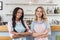 Multiethnic waitresses looking at camera while standing together with arms crossed at cafe