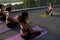 Multiethnic young women meditate with yoga teacher during group class outdoor.