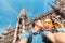 Multinational couple in love hugs and takes a selfie photo on the background of The city hall tower in Munich. Honeymoon