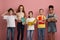 Multinational group of kids with books and notebooks ready for school on pink studio background