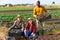 Multinational group of smiling farmers posing with crates at the farm field