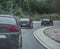 Multiple cars driving together in a column on a cold rainy day. Car enthusiast gathered and going for a road trip. Back view of a