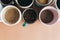 Multiple coffee cups, milk, beans and ground coffee in jar on beige background