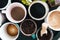 Multiple coffee cups, milk, beans and ground coffee in jar on black background