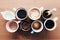 Multiple coffee cups, milk, beans and ground coffee in jar on wooden background