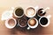 Multiple coffee cups, milk, beans and ground coffee in jar on wooden background