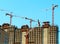 Multiple cranes constructing modern buildings background