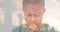 Multiple exposure of african american elementary boy praying with cemetery crosses against sky