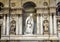 Multiple marble statues of saints on a wall in the Genoa Cathedral