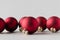 Multiple red matte Christmas balls on a seamless grey background