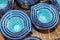Multiple sets of blue ceramic mixing cups with attractive design viewed from top and sitting on wooden table - selective focus