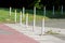 Multiple short metal poles with reflective paint on top put in a row to prevent car entrance or parking