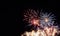 Multiple starburst fireworks over gold sparkling fireworks with a black background