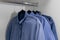 Multiple wrinkled blue shirts hangs in closet