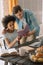 Multiracial boyfriend and girlfriend reading book by table