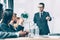 multiracial businesspeople in conference hall listening to team leader while he pointing