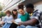 Multiracial college students study together sitting on campus steps.