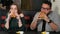 Multiracial couple eating burgers in a cafe.