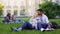 Multiracial couple relaxing on grass, hugging and smiling, first love, students
