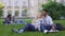 Multiracial couple relaxing on grass, talking and smiling, first love, students