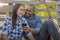 A multiracial couple sits on a deck reviewing selfies