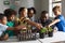 Multiracial elementary school students gesturing on plants at desk in classroom