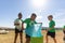 Multiracial elementary schoolboys cleaning plastic in school ground during sunny day