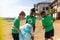 Multiracial elementary schoolboys collecting plastic in garbage bag while standing school ground