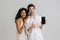 Multiracial excited man and woman gesturing and showing cellphone