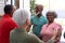 Multiracial friends welcoming african american seniors while standing at doorway in nursing home