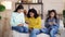 Multiracial girls sitting in living room and using smartphones