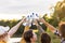 Multiracial group of friends cheering and celebrating outside in nature holding their plastic water bottles in the air