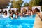 Multiracial group of friends having party in a private villa swimming pool. Happy young people in swimwear dancing and