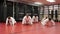 Multiracial group of men and women warming up before karate training and doing push-ups in gym.