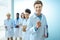 Multiracial group of smiling medical interns in lab coats standing in a row with clipboards