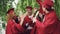 Multiracial group of young people students are doing high-five on graduation day wearing traditional clothes hats and
