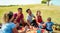 Multiracial happy families doing picnic in nature park outdoor - Young parents having fun with children in summer time - Food and