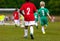 Multiracial kids kicking football on the sports field